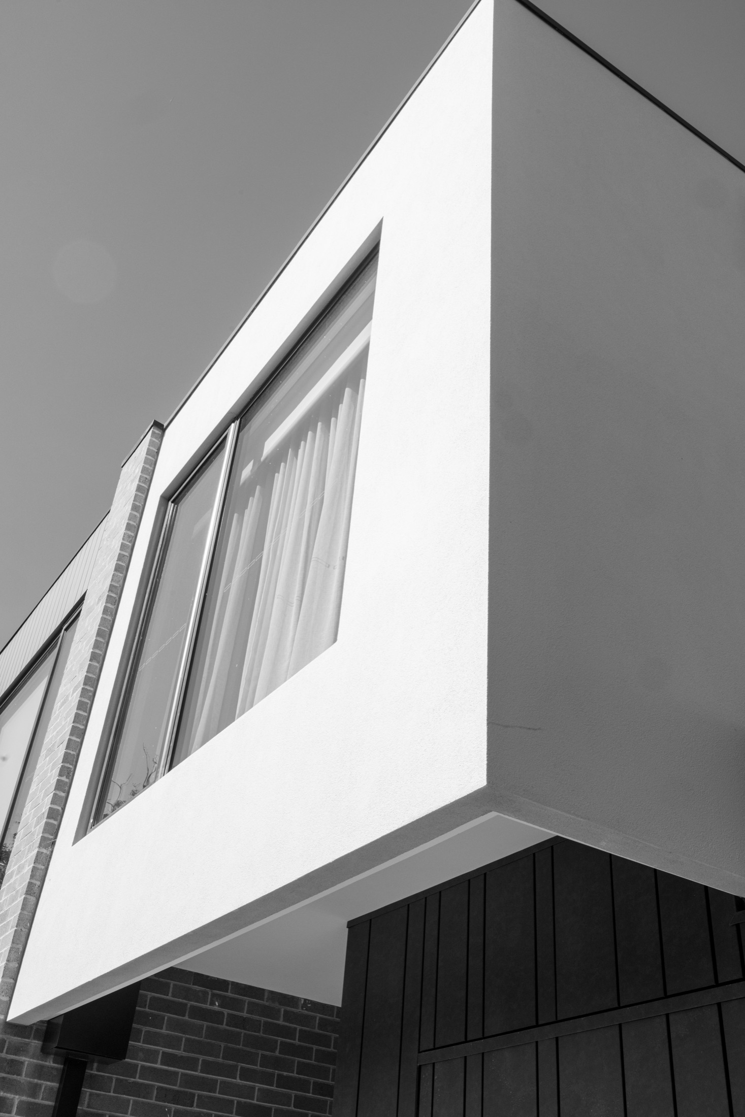 Black and white detail of the rendered upper storey and deep window reveal