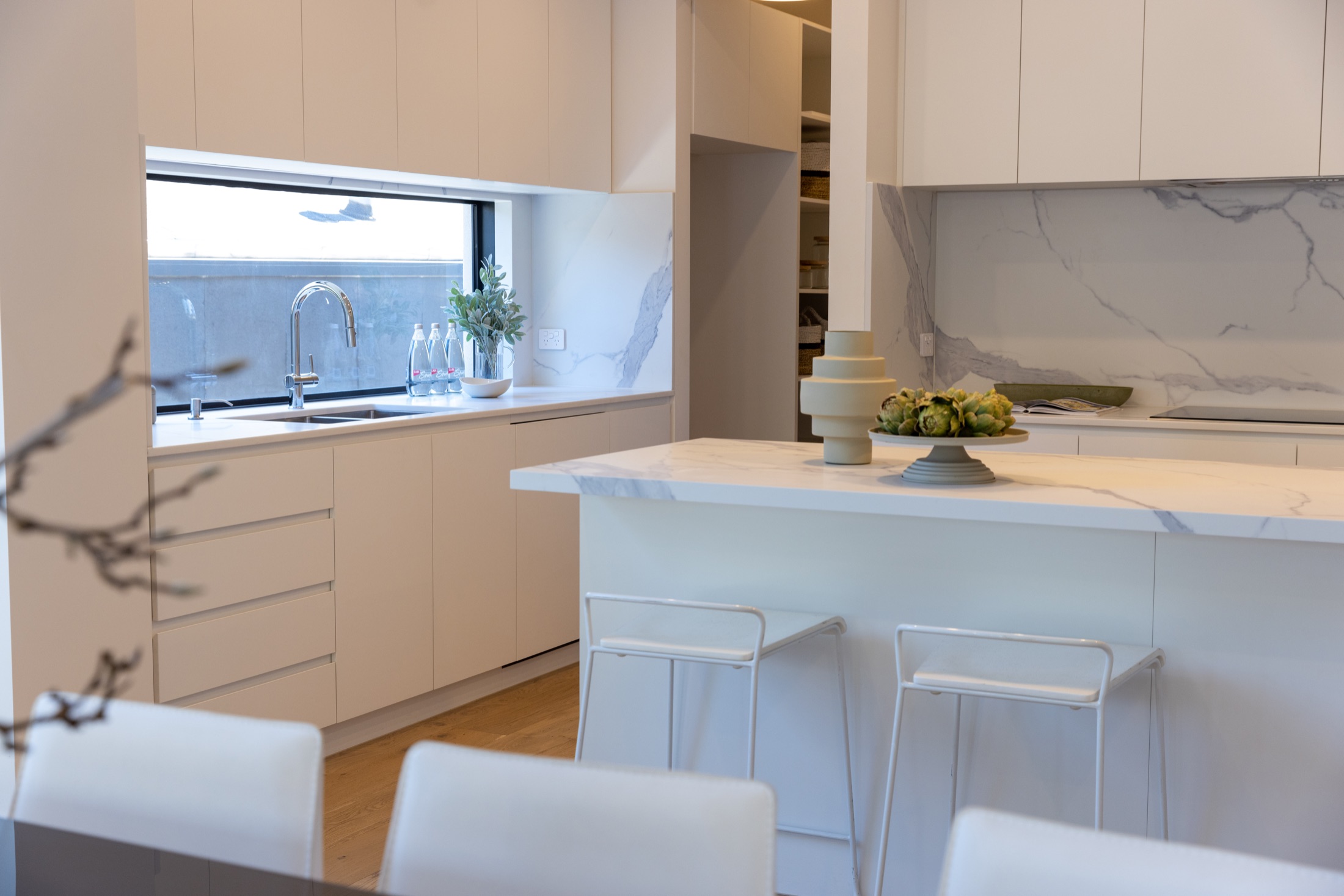White kitchen joinery, stone splashback and island viewed from the dining area