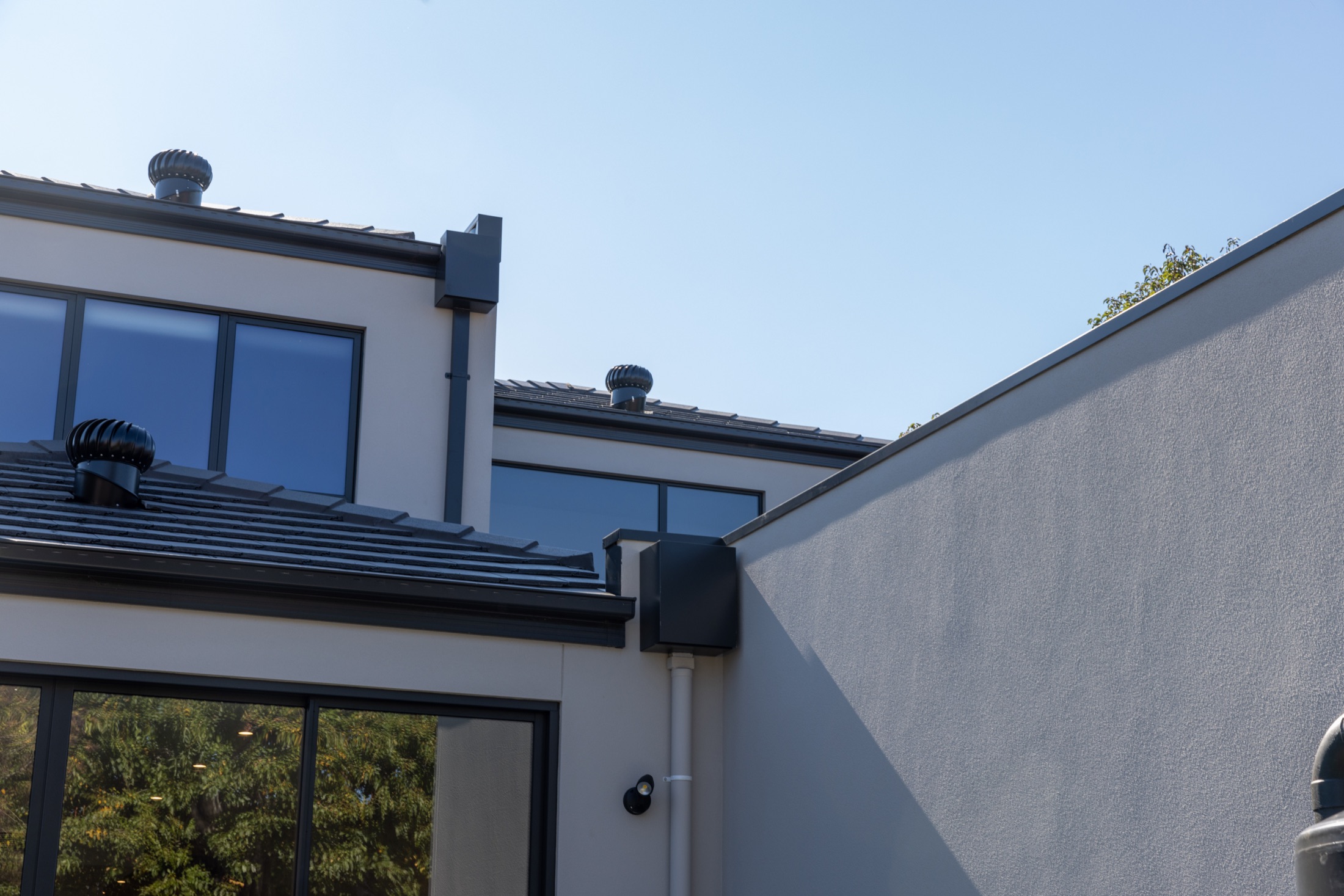 Rear elevation detail showing dark window frames, roof drainage and rendered walls
