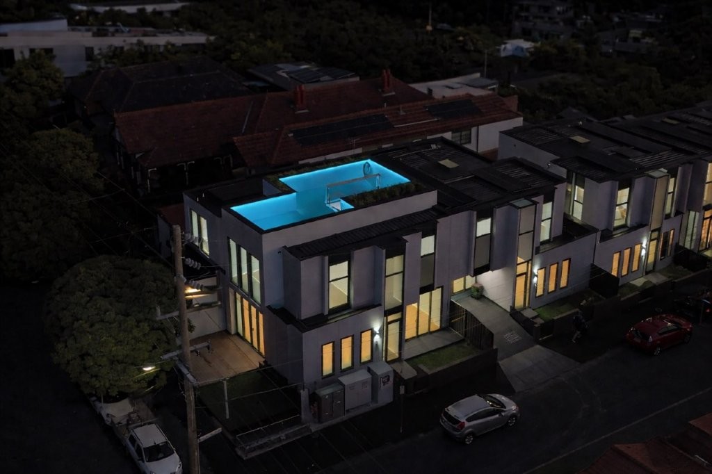 The Barkly Street townhouses at dusk, four dwellings on a corner block with a lit rooftop terrace