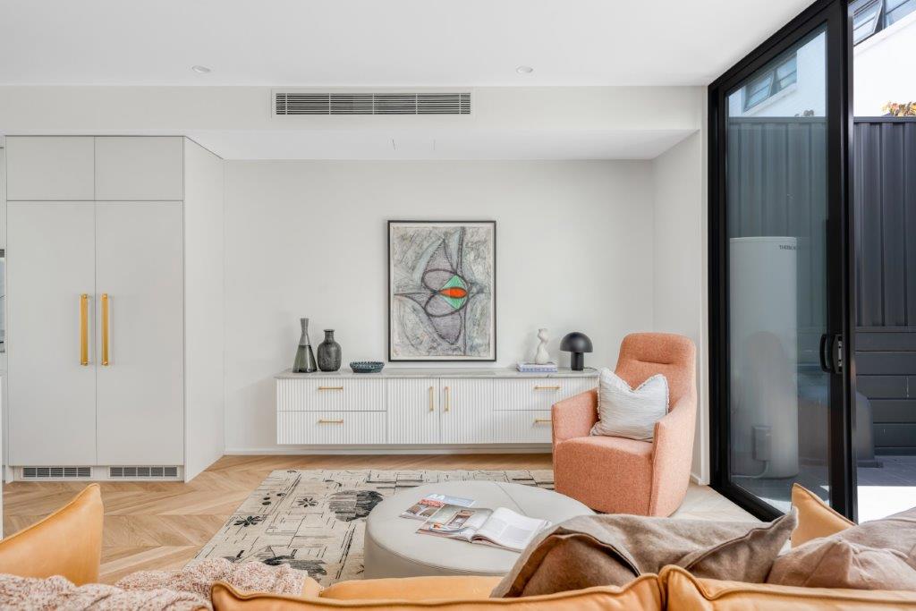 Living room at Barkly Street with fluted joinery, gold handles and herringbone timber floors